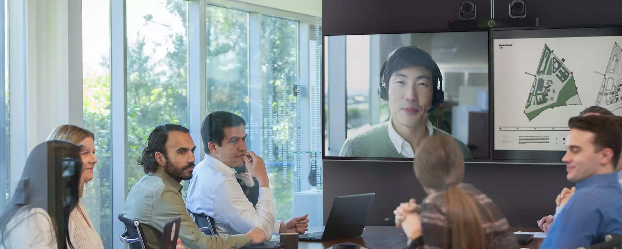 meeting room with staff and remote worker on screen