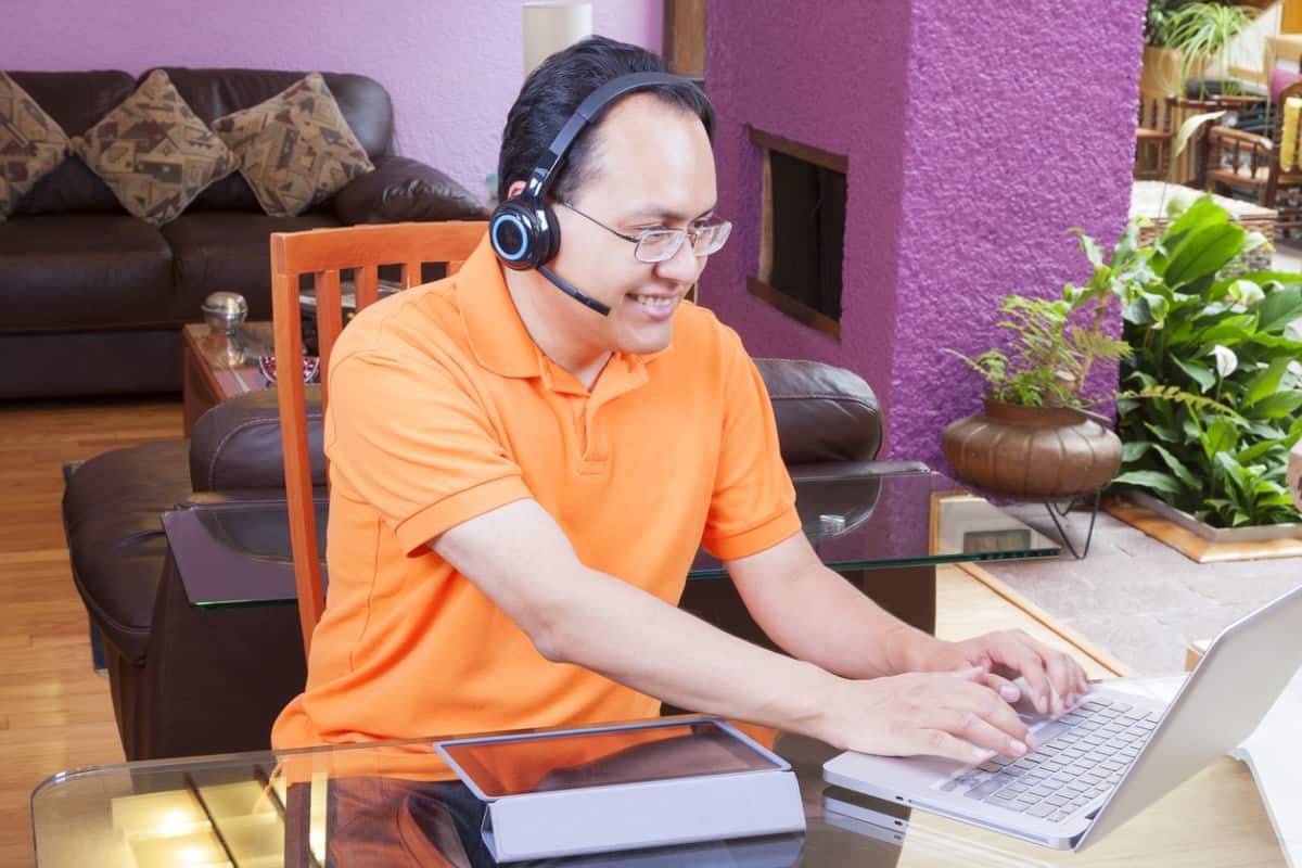 man sitting at desk talking through headset while working