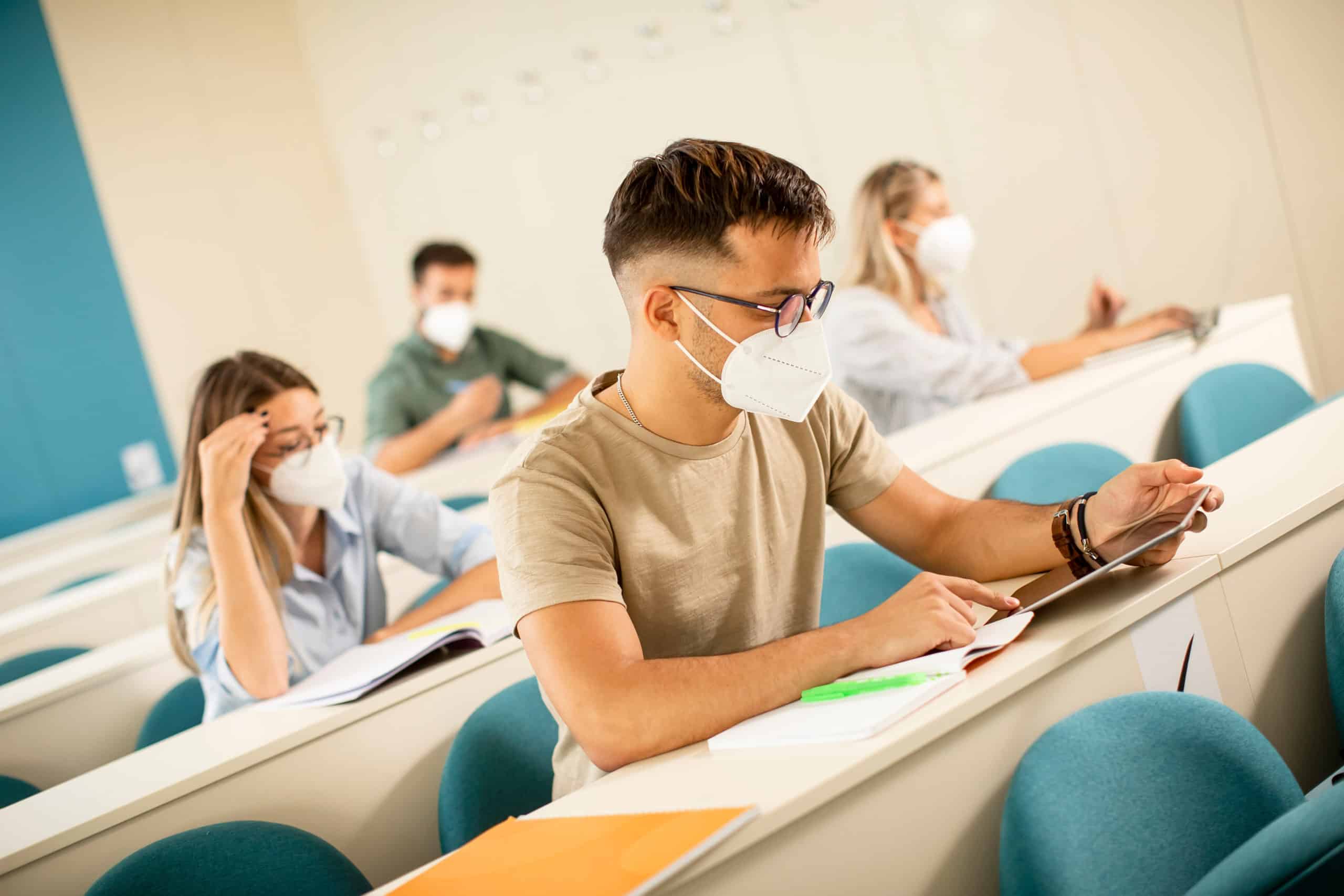 student in college lecture hall wearing mask