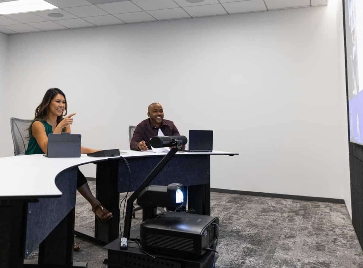 Two meeting space presenters talking to virtual attendees in a Microsoft Teams Room
