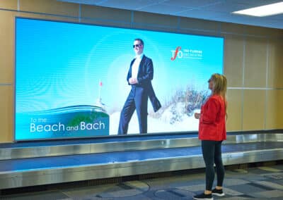 woman in front of airport baggage claim video wall