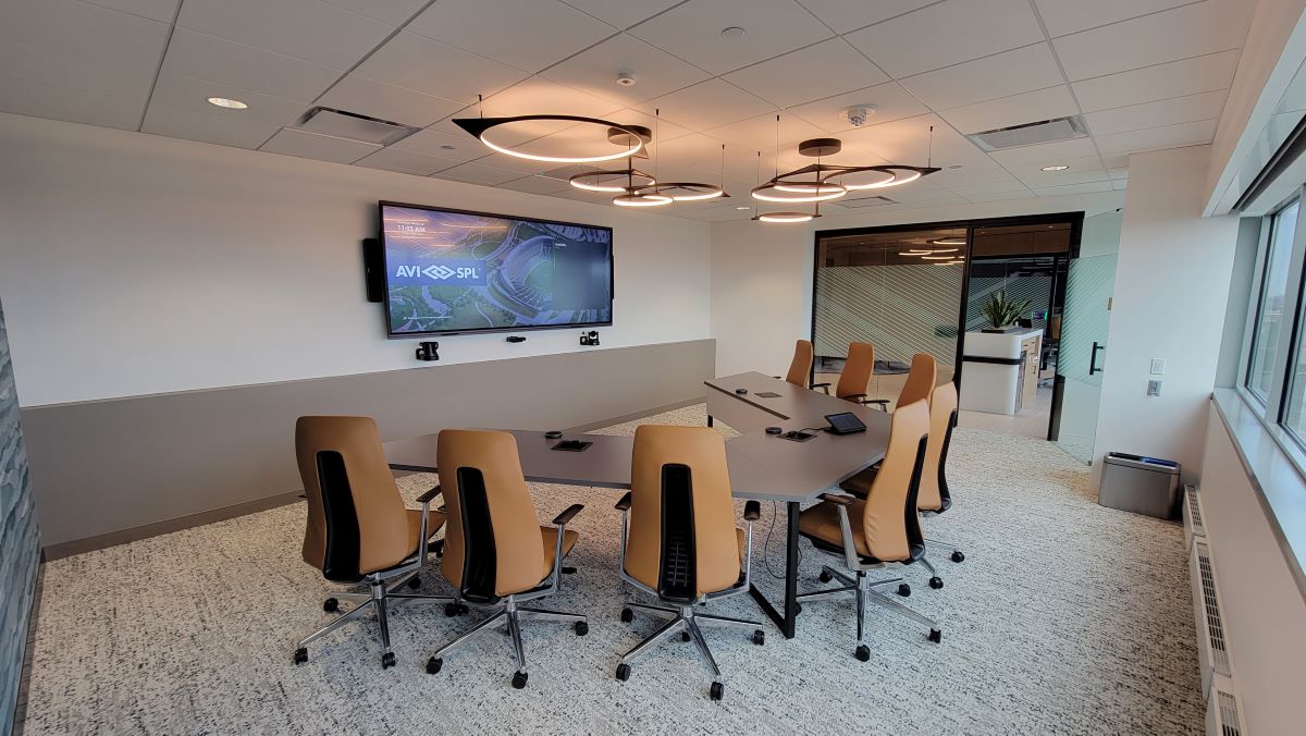 Modern conference room: long table, 8 ergonomic chairs, large screen, circular ceiling lights, big window.