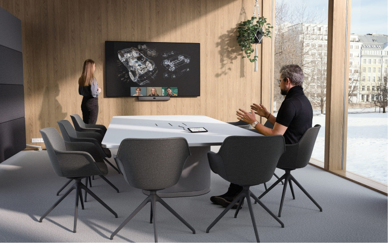 Modern conference room: large screen with video call & car design. Two people, snowy landscape visible through big windows.