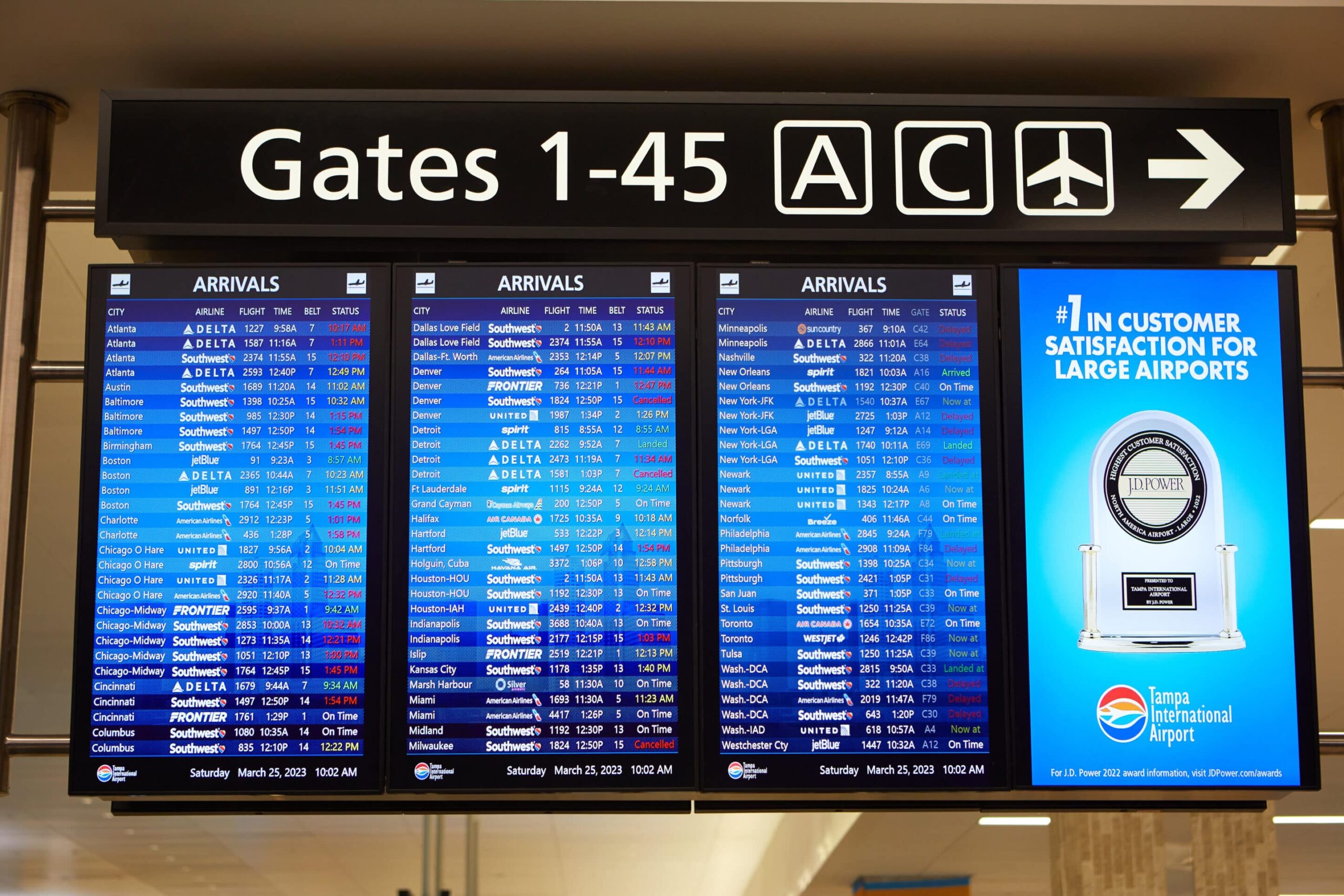 Airport board shows arrivals from Orlando, Chicago, Miami. Sign highlights Tampa Intl Airports customer satisfaction award.