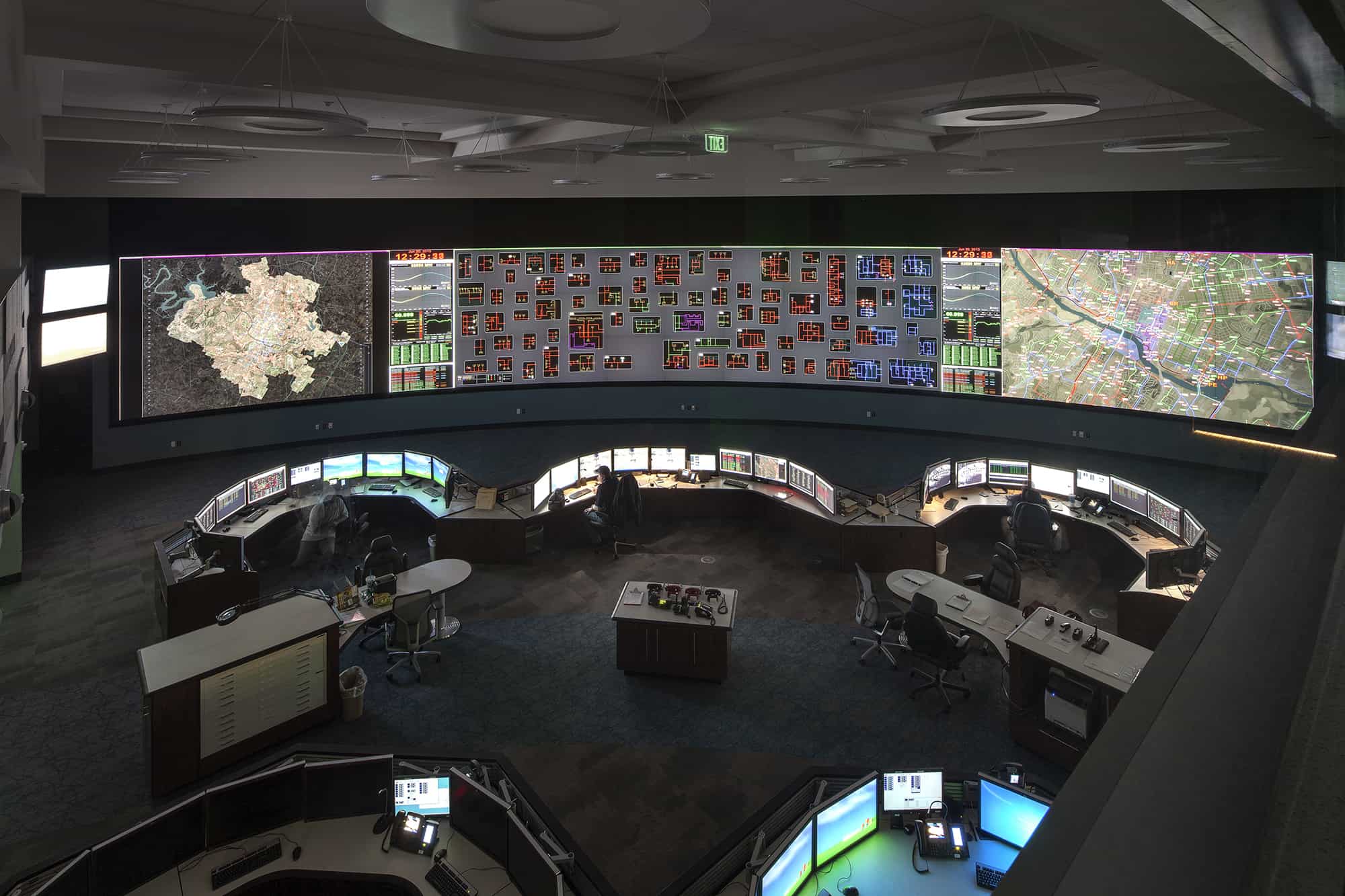 military personnel in command and control room featuring a video wall