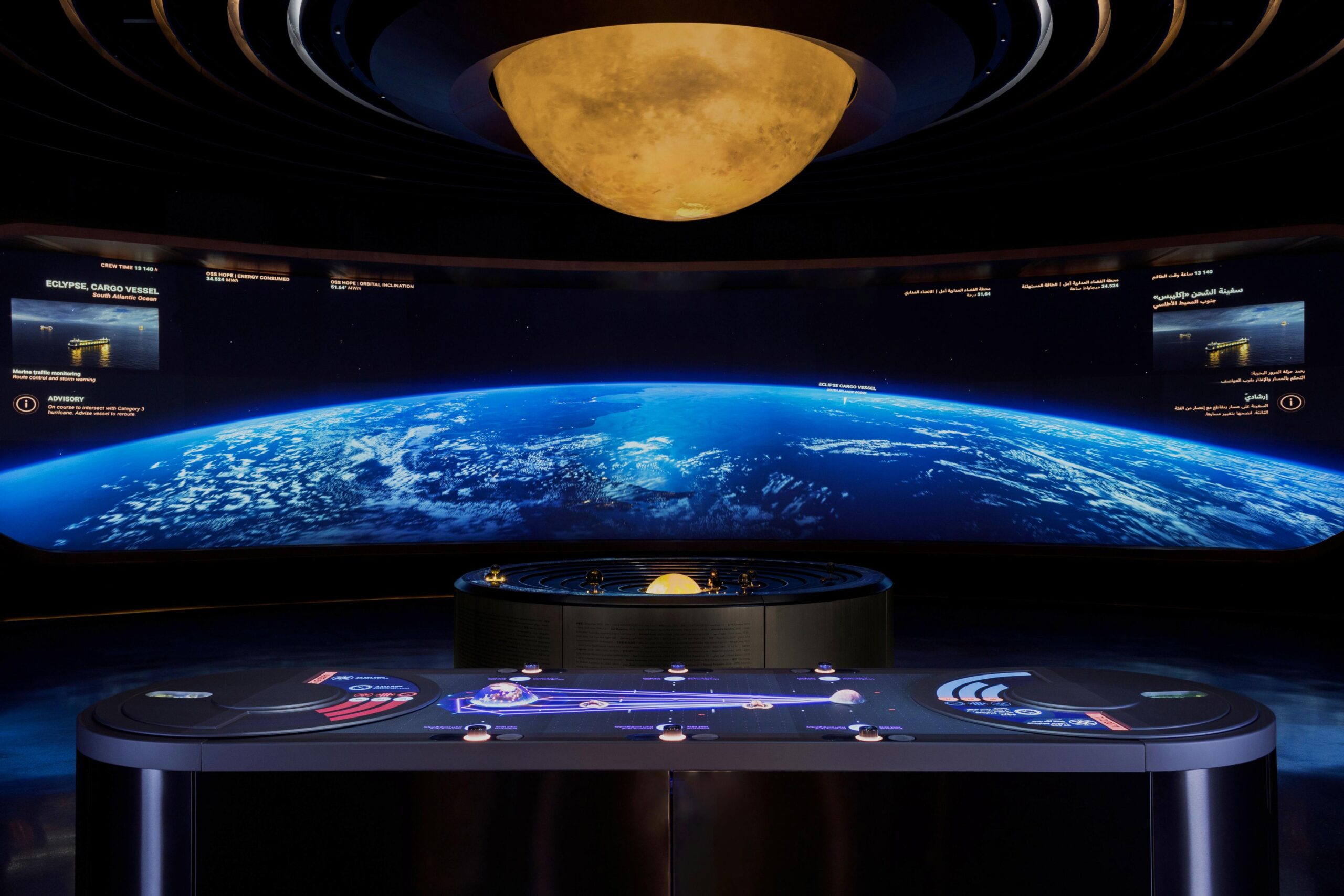 Futuristic control room with Earth view, interactive panels, holographic display, and a glowing circular structure as ceiling light.