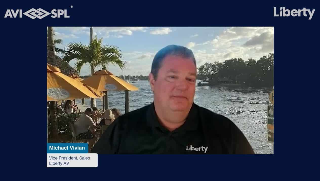 Michael Vivian, Vice President of Sales, Liberty AV sits in front of a scenic waterfront. Logos for AVI SPL and Liberty are displayed.