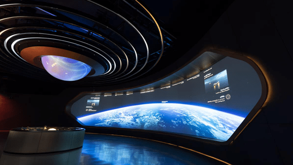 A futuristic room with a curved screen showing Earth from space, circular orbit lights, and a dim, high-tech vibe.