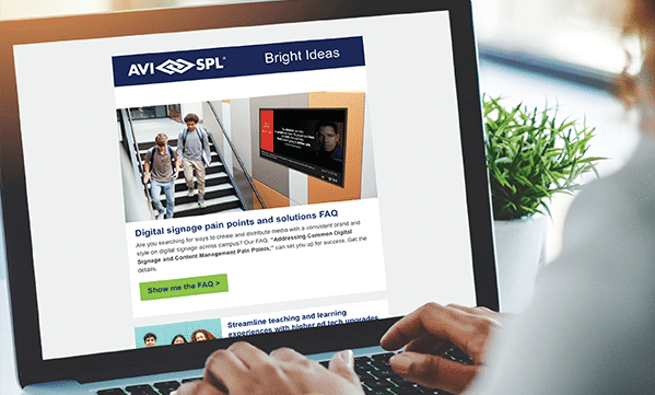 Person with a laptop showing AVI-SPL email Bright Ideas on digital signage, people on stairs image, teaching tips, FAQ button.