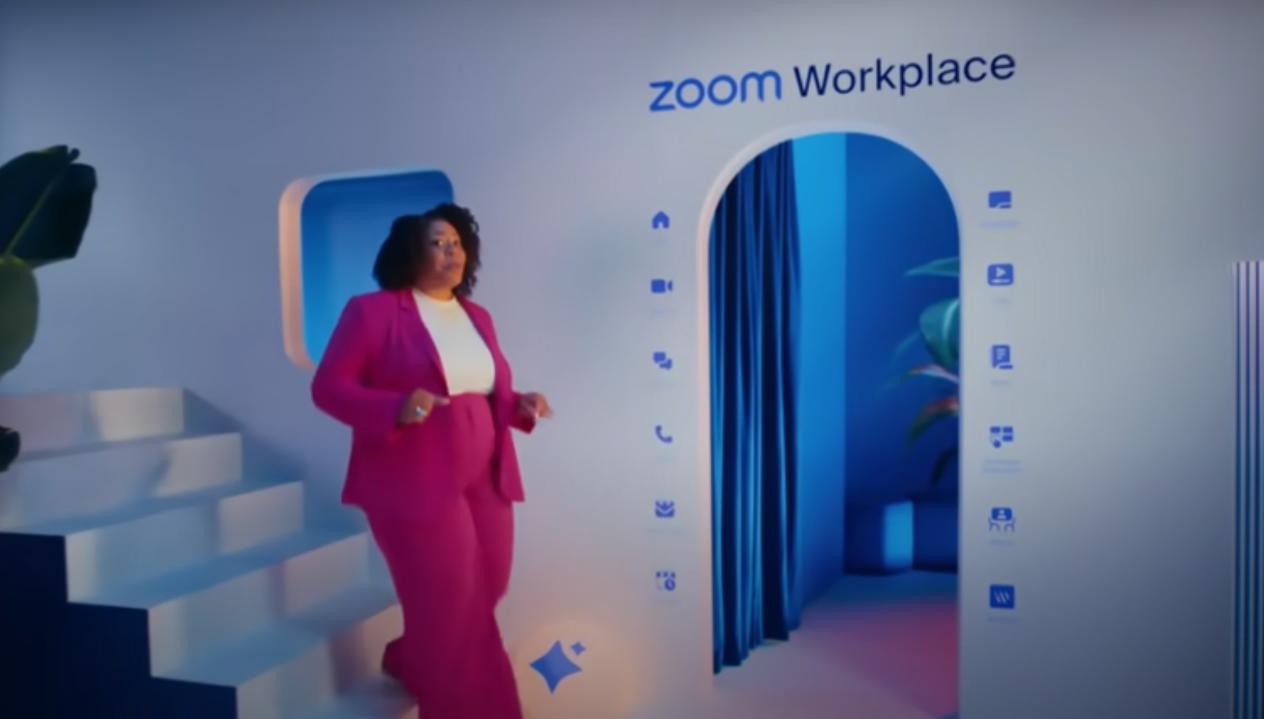 A person in a pink suit descends white stairs, passing the Zoom Workplace logo; sleek setting with blue lighting and a plant.