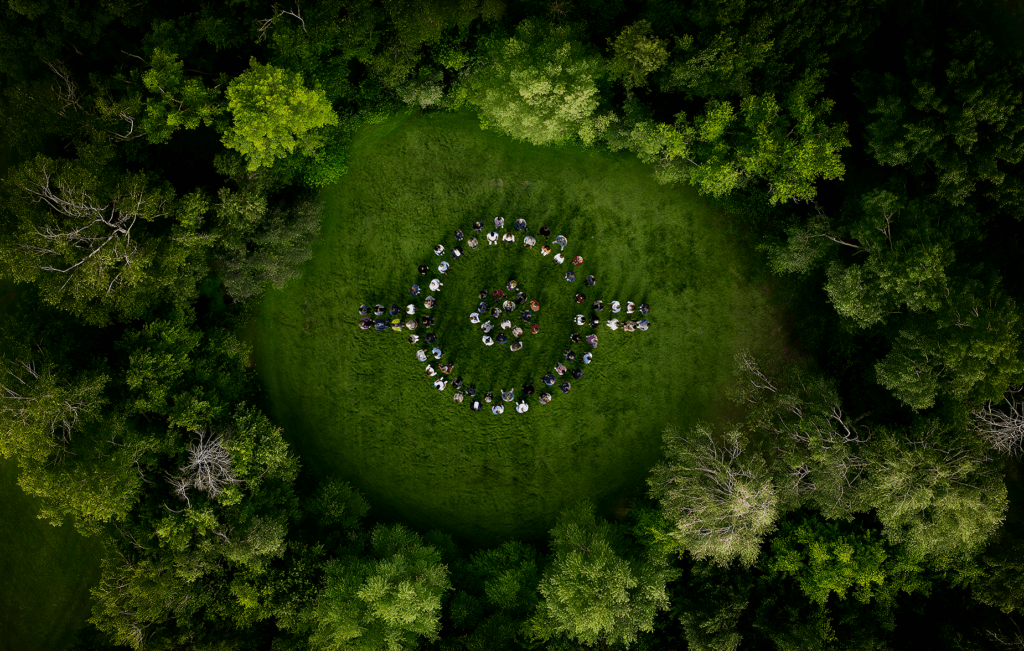People standing in a forest clearing in the Barco logo