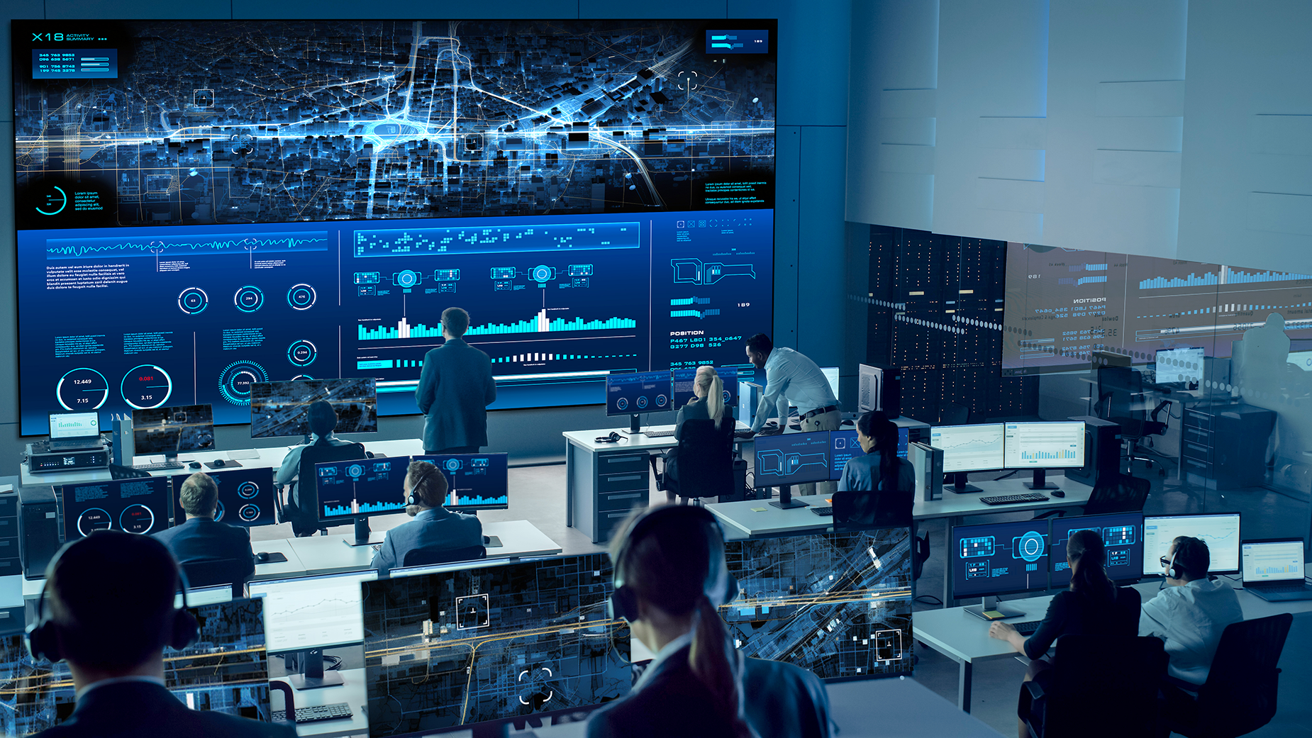 Federal government team members working together in a command center using desktop monitors and a video wall to coordinate and communicate.