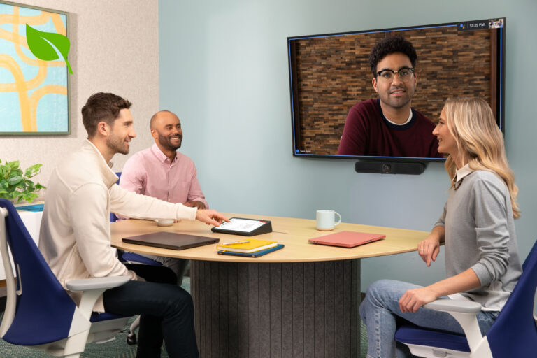 Three people host a hybrid meeting in a small meeting space with sustainable Logitech devices.