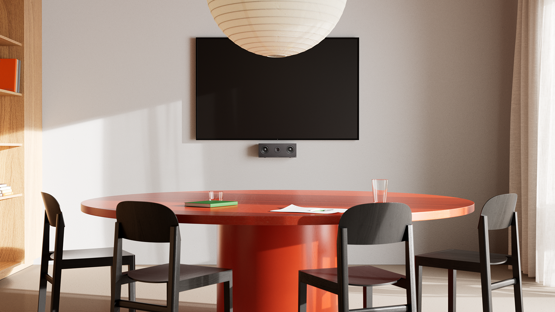 Small meeting space with four chairs surrounding a circular table in front of a wall with a mounted Huddly C1 and a digital display. 