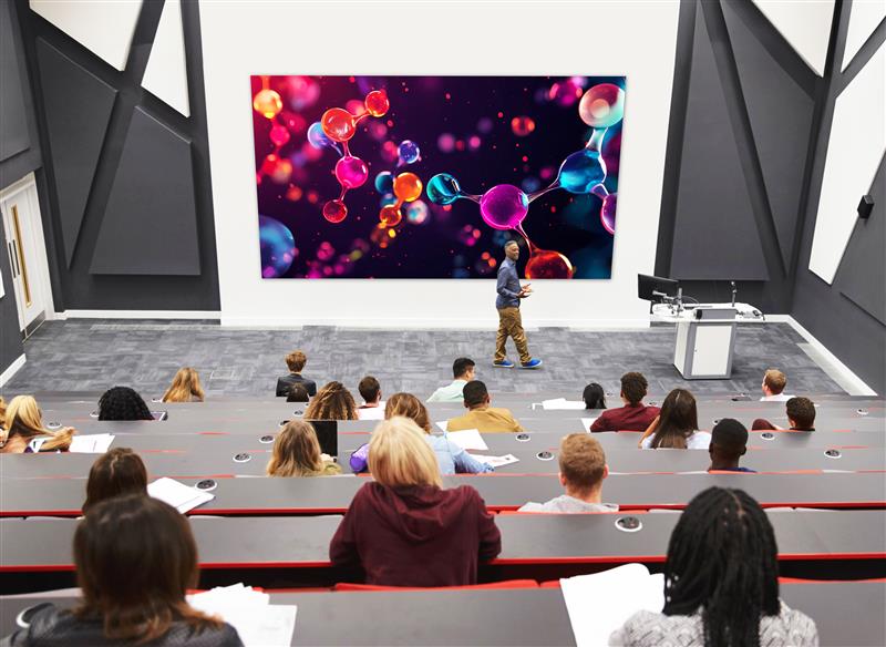 A professor shares a presentation with students via a large-format lecture hall display.