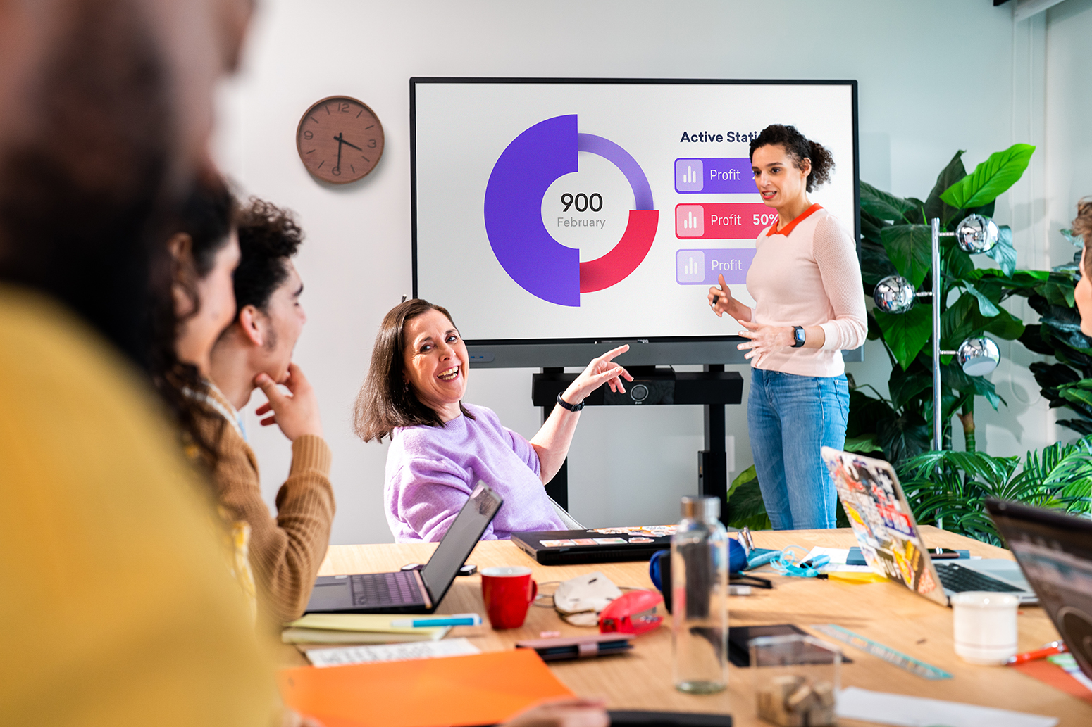 Woman points to the display during a secure hybrid meeting.