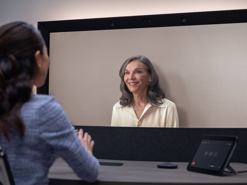 Two people use HP Dimension and Google Beam to host a virtual meeting. The AI-driven AV and UC system renders on-screen people three-dimensionally without glasses.