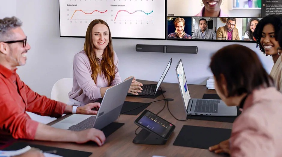 Team huddled around a desk hosting a hybrid meeting.