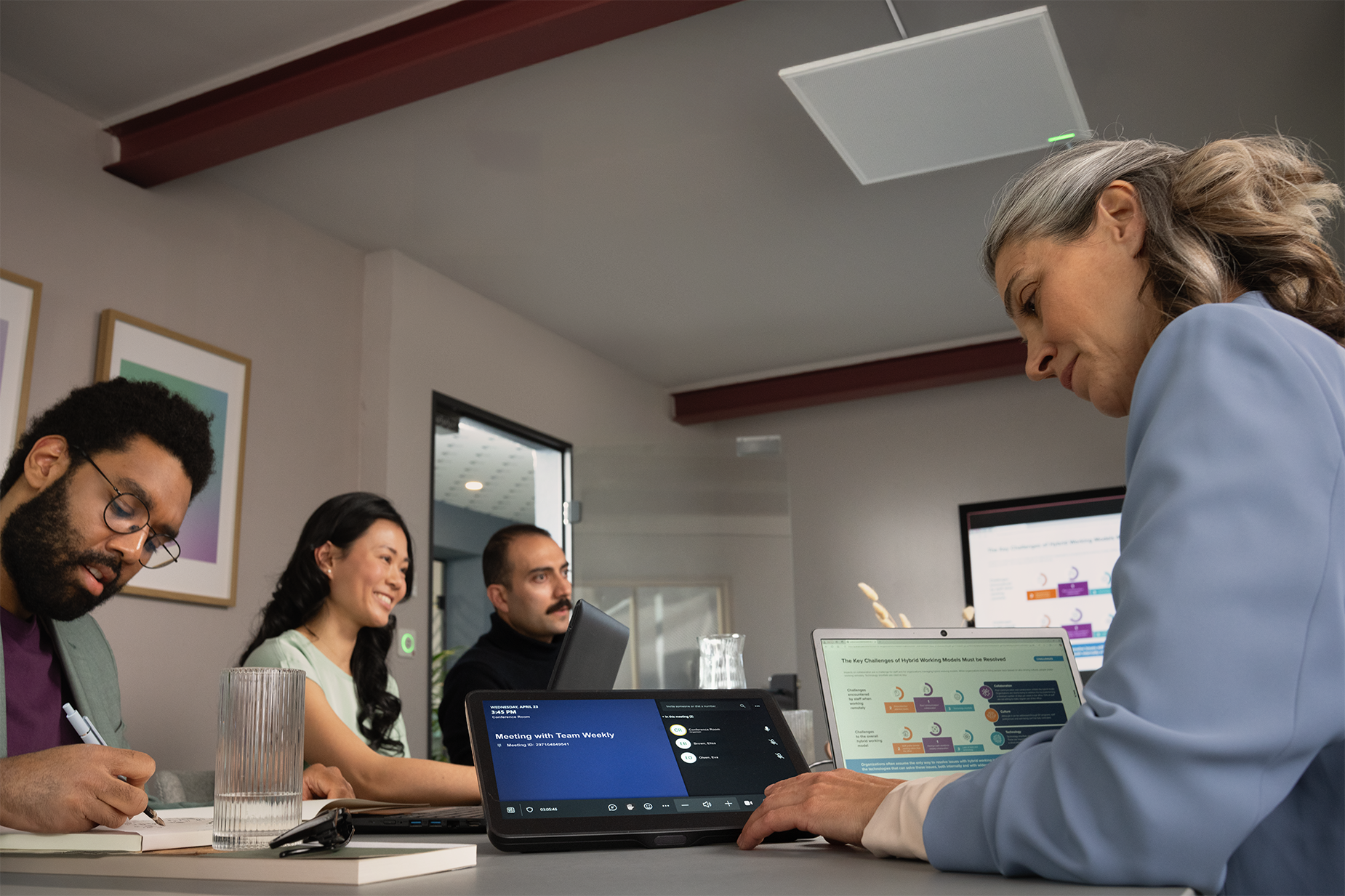 A person in a small meeting space looks at the Shure IntelliMix intuitive touch panel to add remote attendees to the hybrid meeting.