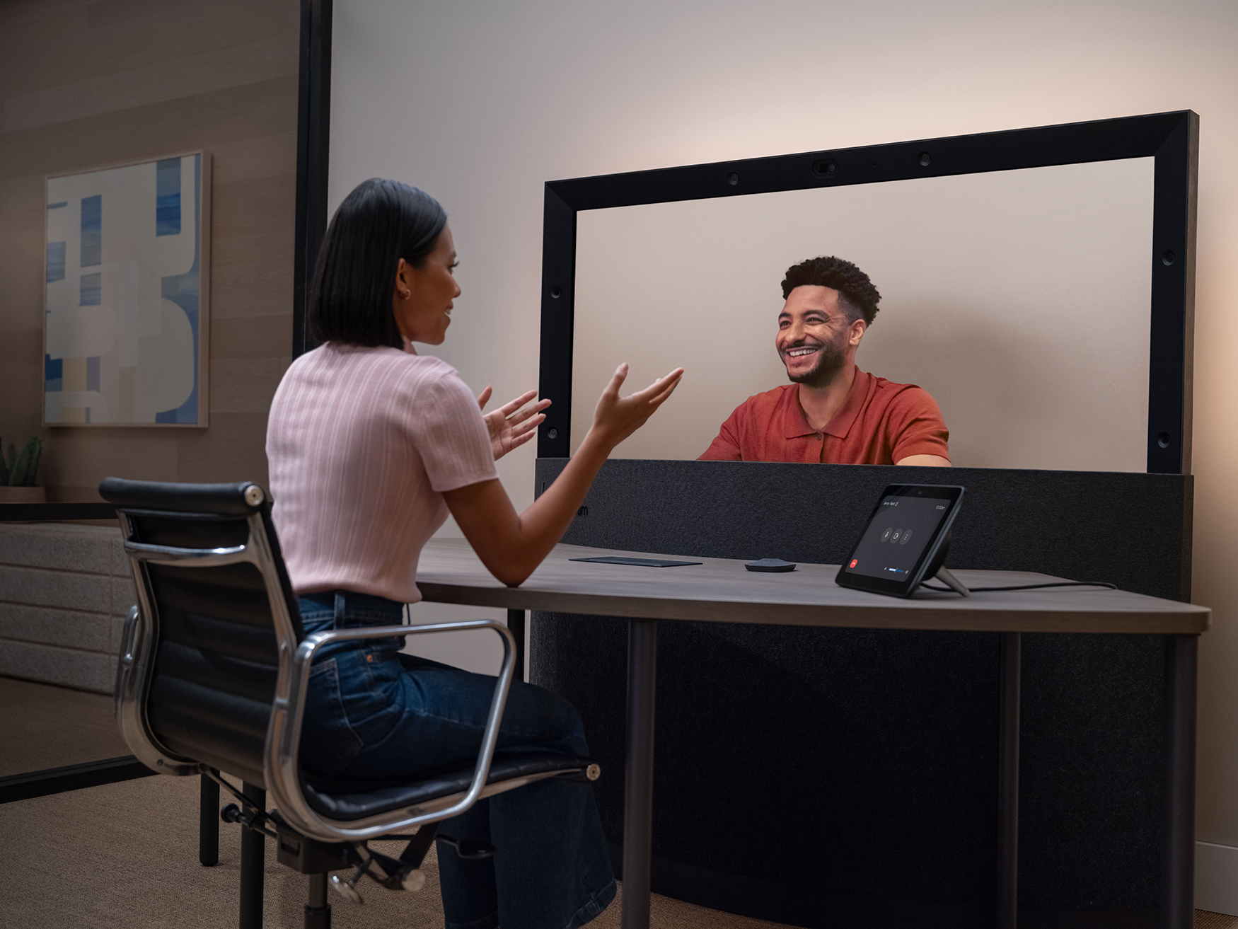 A woman sitting at a semi-circle speaking to a virtual meeting attendee using HP Dimension with Google Beam