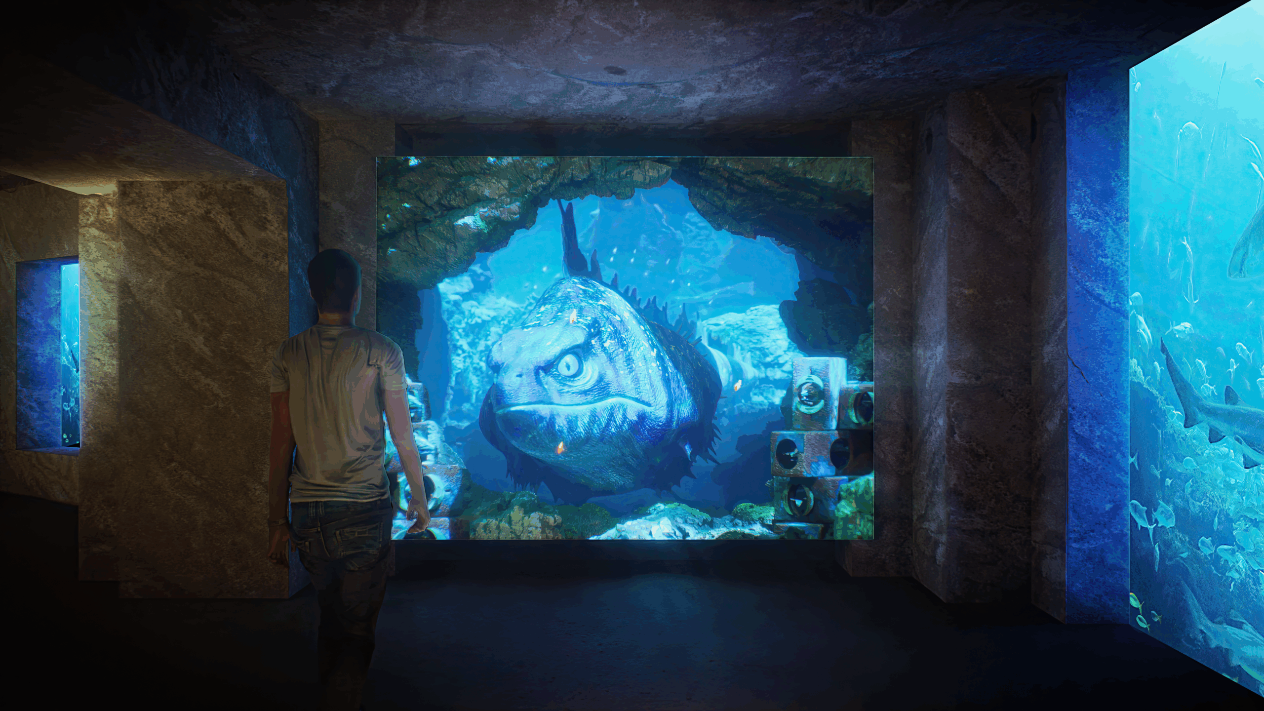 A person interacts with a floor-to-ceiling video projection of a fish in the Lost World aquarium corridor.