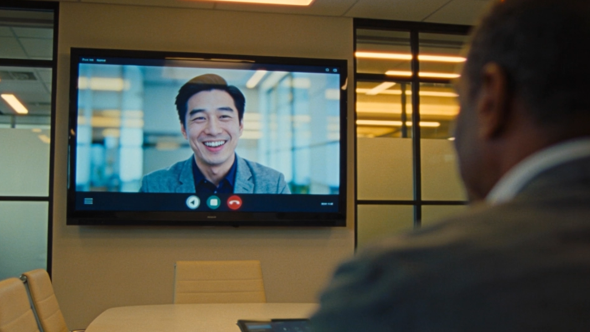 Hybrid meeting in a modern conference room with a one in person and one remote person on large display