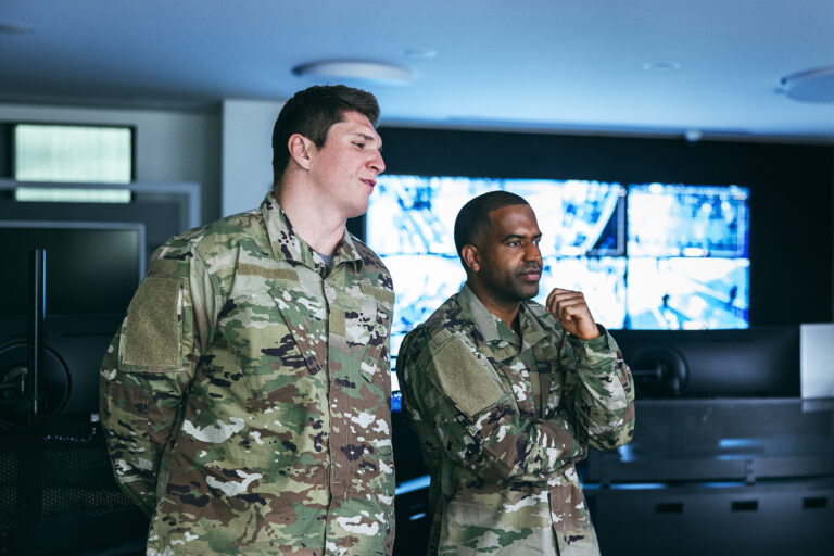 Two-soldiers-standing-in-front-of-a-video-wall-in-command-center-768x512