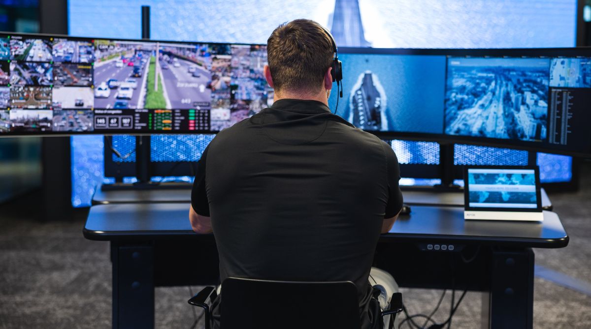 Man in real-time crime center control room monitoring Samsung displays and video wall